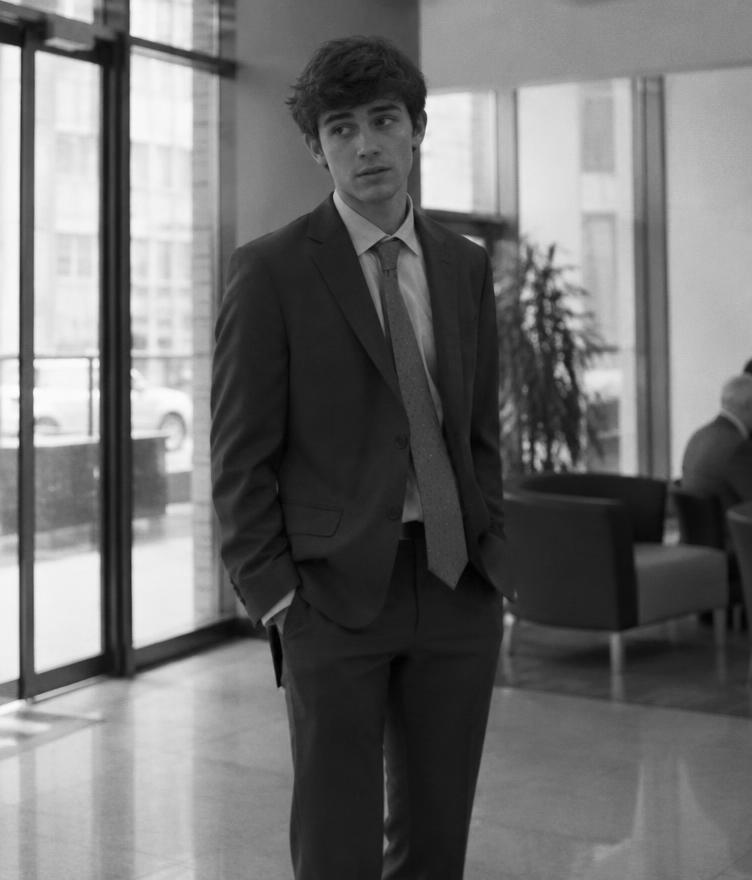 A young sales professional standing uncertainly in an office lobby